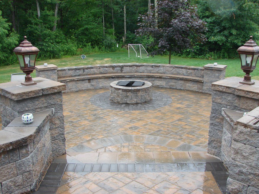 Paver patio with curved sitting wall, entry piers, and a centered fire pit