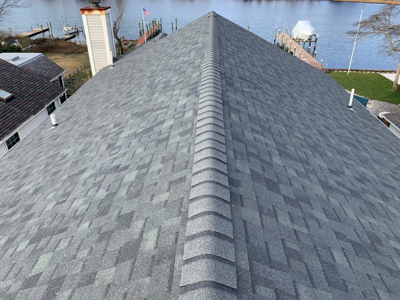 Completed waterfront roof replacement with new ridge caps and architectural shingles