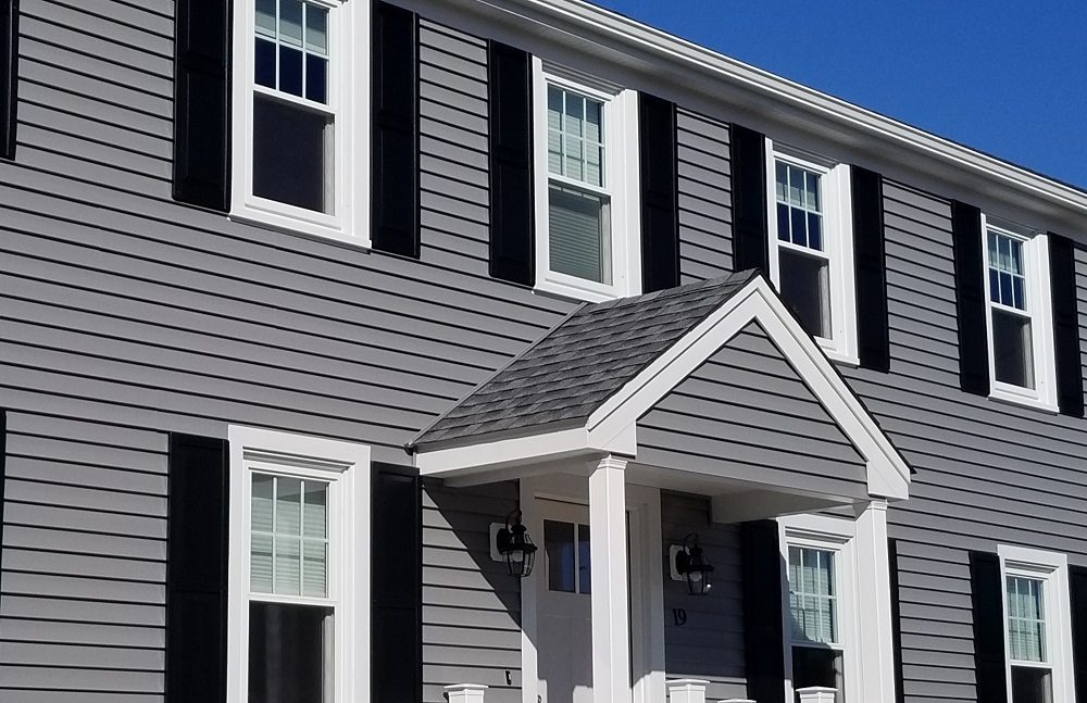 Grey horizontal siding with black shutters and crisp white trim on a colonial home